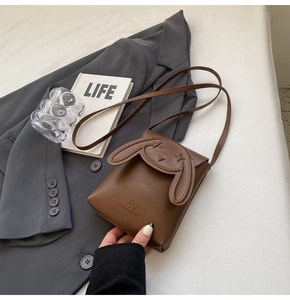 Detail view of a brown rabbit-shaped crossbody bag with cute ears and brand logo