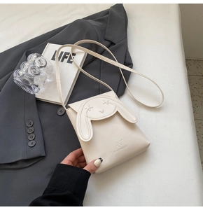Detail of cute cream crossbody bag with rabbit ear flap and debossed logo on premium leather