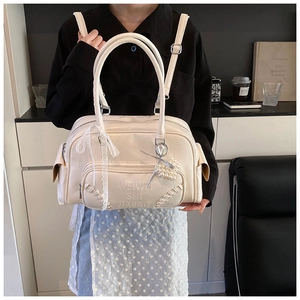Dettaglio borsa in pelle sintetica bianco crema con fiocco in pizzo e ciondolo di perle