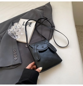 Detail of black crossbody bag featuring cute cartoon rabbit ears and stylish strap