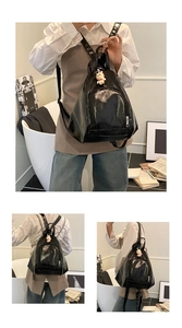 Détail du sac à dos en cuir noir brillant avec poche avant et breloque chat blanc