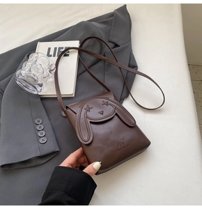 Close-up of brown mini crossbody bag featuring a cute 3D rabbit relief and smooth texture