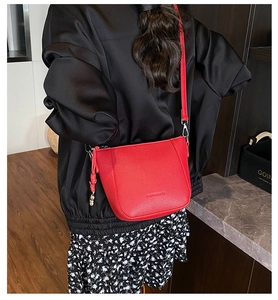 Close-up of red lychee grain leather bucket bag with zipper tassel on floral dress