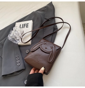 Detail of dark brown leather crossbody bag featuring a cute embossed cartoon rabbit design