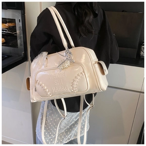 Dettaglio borsa in pelle bianco crema con logo a rilievo e ciondolo di perle