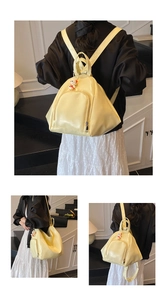 Détail du sac à dos jaune crème brillant avec forme triangulaire et breloque mignonne