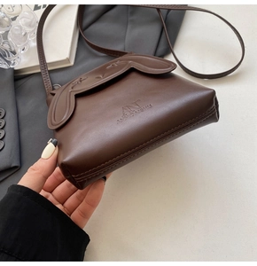 Detail of bunny ear flap design and star embossing on dark brown leather crossbody bag
