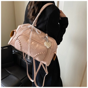 Dettaglio dello zaino in pelle rosa con fiocco di pizzo, cuore di perle e scritte a rilievo