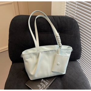 Détail d'un sac cabas plissé vert menthe avec mini pochette assortie sur un fauteuil noir