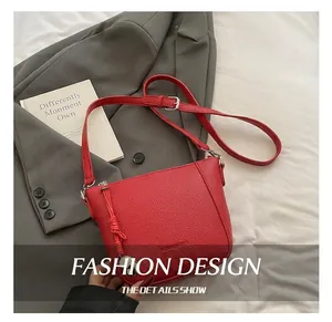 Detailed macro view of red crossbody bag with litchi texture and silver hardware