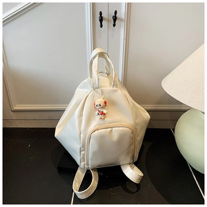 Gros plan d'un sac à dos blanc brillant avec pendentif lapin et design géométrique