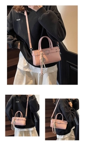 Detalle de bolso en cuero charol rosa claro con hebilla de metal y borla de adorno