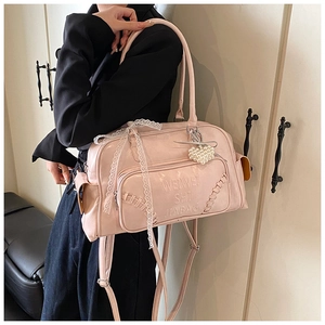 Dettaglio borsa Boston rosa con fiocco di pizzo, ciondolo a cuore di perle e logo