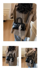 Detalle de bolso de charol negro con borla de nudos y correa de hombro ajustable