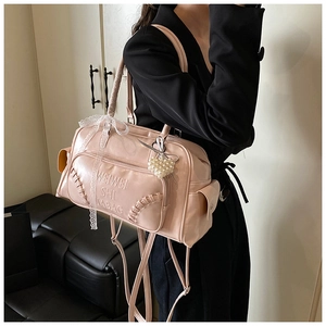 Dettaglio borsa Boston rosa con testo a rilievo, fiocco in pizzo e ciondolo cuore