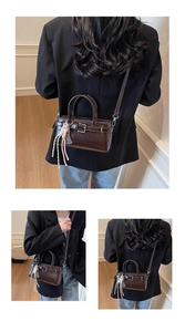 Vista de detalle de un bolso bandolera retro marrón oscuro con hebilla de metal y dijes