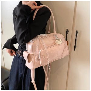 Dettaglio della borsa tote in pelle rosa con fiocco in pizzo bianco e ciondolo a cuore