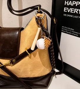 Primer plano de llavero de béisbol con guante y bate en un bolso de mano marrón