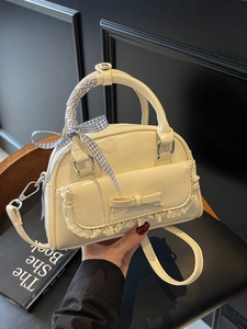 Elegant off-white crossbody bag with lace trim, bow detail, and ribbon-wrapped handle