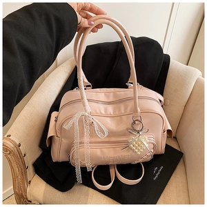 Dettaglio borsa Boston rosa con fiocco di pizzo bianco e ciondolo a cuore di perle
