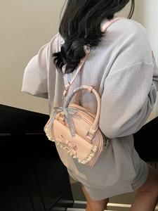 Pink minimalist crossbody bag with lace trim and bow handle shown as a stylish backpack