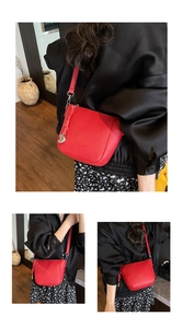 Close-up of red lychee textured crossbody bag with heart charm and brand logo