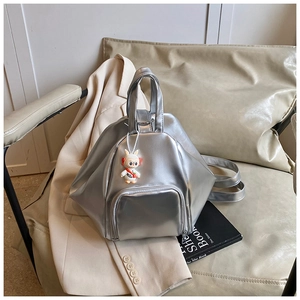 Sac à dos géométrique argenté avec charme lapin posé sur un fauteuil en cuir crème