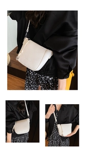 Close-up of white lychee pattern leather crossbody bag with knot strap and metal pendant