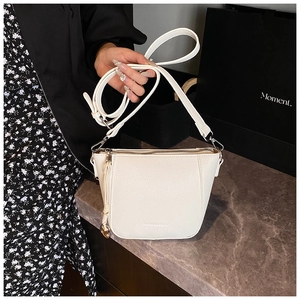 Detailed shot of a white bucket bag in pebble leather with adjustable strap and metal charm