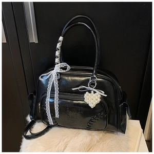 Dettaglio borsa nera lucida con ciondolo a cuore di perle e fiocco in pizzo decorativo