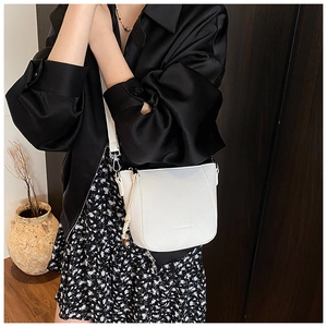 Detail view of white lychee textured crossbody bucket bag with silver zipper on a model
