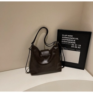 Détail du sac bandoulière en cuir marron foncé avec rabat et bandoulière minimaliste