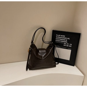 Détail du sac bandoulière en cuir marron foncé avec boucle dorée et rabat magnétique