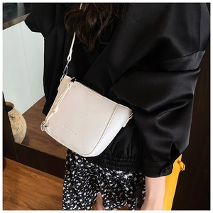 Detail of white lychee pattern leather crossbody bag with silver zipper and woven cord