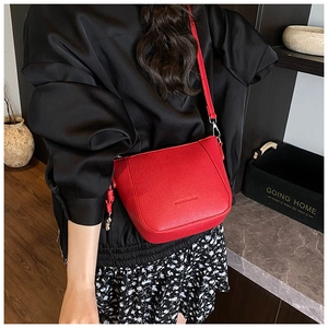 Detail view of a red lychee pattern leather bucket bag with silver hardware and strap
