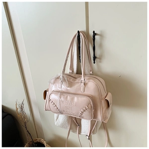 Dettaglio borsa bowling in pelle verniciata rosa con logo in rilievo e nastro di pizzo bianco