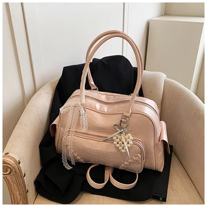 Borsa in vernice rosa con fiocco di pizzo e ciondolo a cuore di perle in dettaglio
