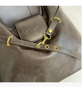 Détail d'un sac cabas en cuir marron foncé avec boucles dorées et logo embossé chic