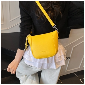 Detail of yellow pebbled leather bucket bag with silver hardware and shoulder strap