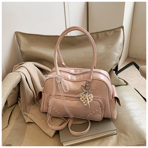 Borsa Boston rosa su sedia beige con ciondolo a cuore in perla e fiocco in pizzo