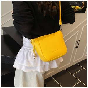 Detailed view of the vibrant yellow pebbled leather bucket bag worn as a crossbody bag