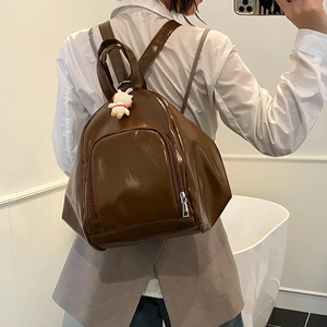 Sac à dos marron en cuir PU brillant avec breloque chat montré dans un selfie miroir