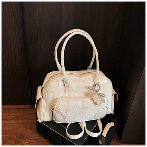 Dettaglio borsa in ecopelle bianco crema con testo a rilievo, fiocco in pizzo e perla