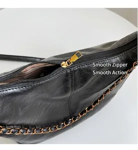 Close-up of black leather tote bag with gold zipper and chain strap detail