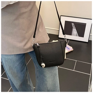Detail of black pebble texture crossbody bucket bag with silver hardware and charm