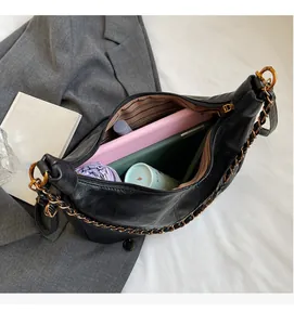Top view of large capacity black leather tote with chain strap and striped lining detail
