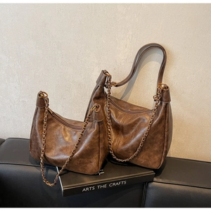Detail of dark brown vintage crescent tote bags with retro chains and oil wax texture