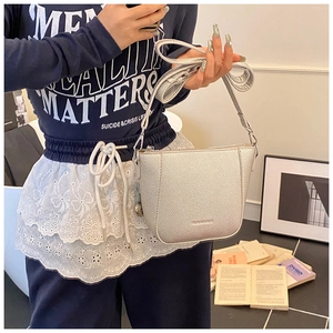 Silver bucket bag with litchi texture and chain strap worn by a model in casual style