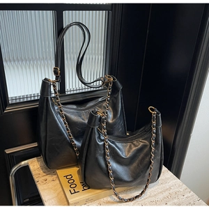 Detail shot of black hobo bags featuring gold chain straps and smooth PU leather texture