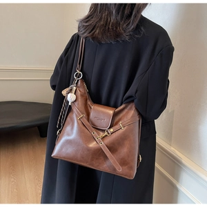 Détail du cabas vintage en cuir marron ciré avec gaufrage mode et breloque baseball